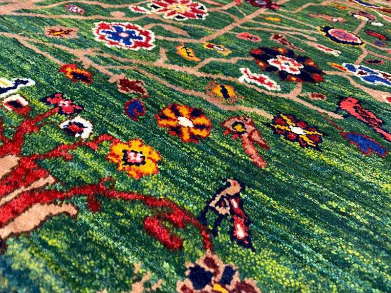 Close-up of a green carpeted surface with colorful floral ornaments and plants
