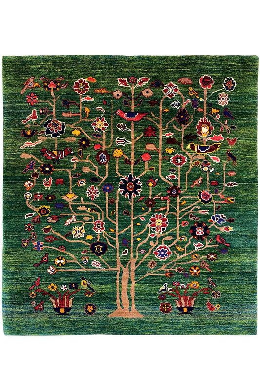 Green Oriental rug with a central tree motif, colorful flowers, and red accents