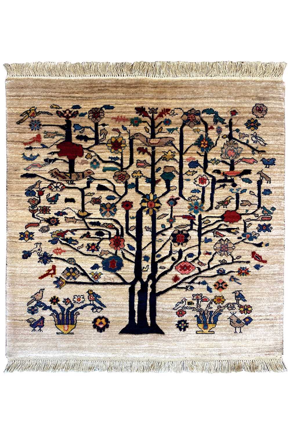Square beige rug with a tree motif, colorful birds and flowers, fringed edges.