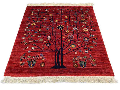 Red Oriental rug with a central tree, colorful ornaments, and beige fringes.