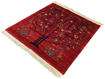 Red oriental rug with a tree motif and colorful ornaments, beige fringe trim, angled.