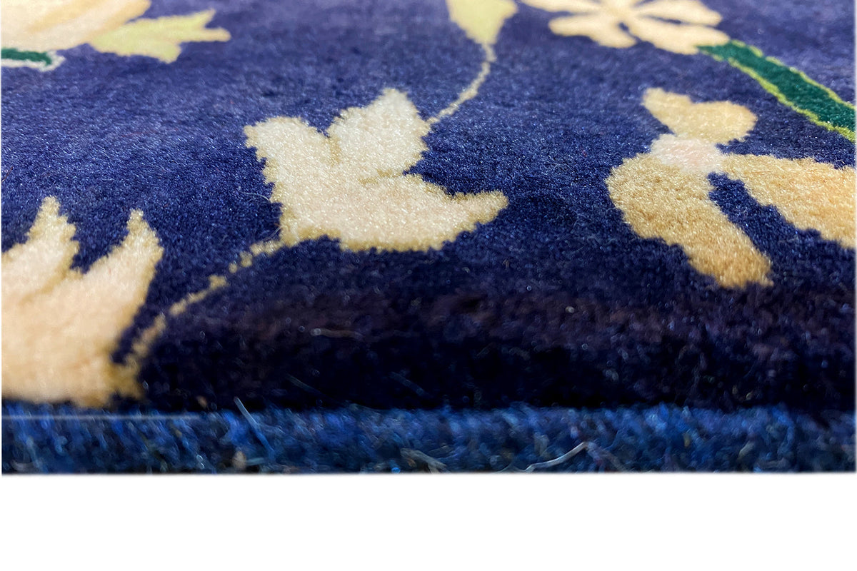 Carpet fabric in detail, dark blue with light-colored flowers and a floral pattern, fringe
