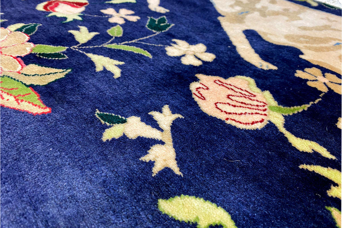 Close-up of a dark blue carpet with colorful dog and leaf motifs, with the pile height visible