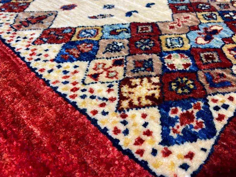 Close-up of a rug: cream-colored medallion, blue and red ornamental panels, short pile