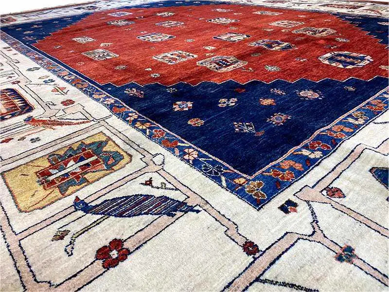 Oriental rug corner with a red central field, dark blue border, and cream-colored medallions