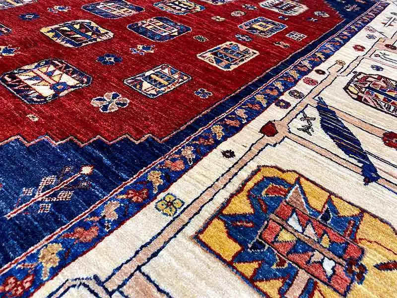 Detail view: red Oriental rug with a blue border and beige ornamental stripe