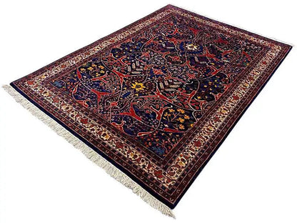 Oriental rug in dark blue and red with a central medallion, photographed at an angle
