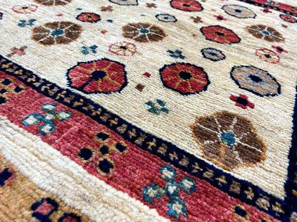 Close-up of a rug: circular patterns, red and blue tones on a beige background