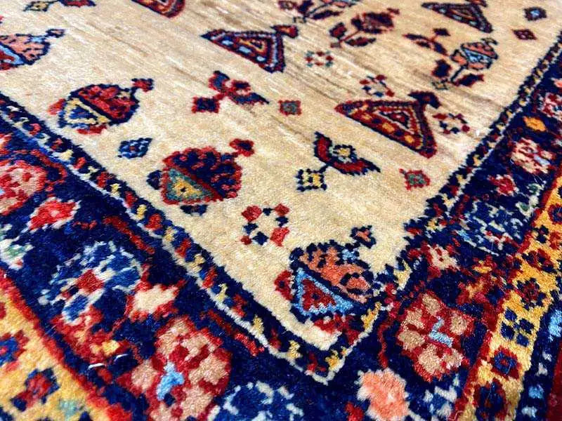 Carpet pile with a beige base and colorful geometric patterns in blue, red, and yellow