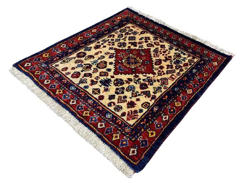 Square Oriental rug in a diamond pattern with a border, cream-colored center, and fringes