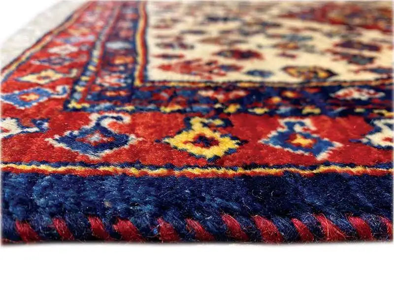 Oriental rug detail with blue pile and a red stripe pattern along the edge