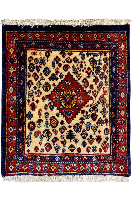 Square Oriental rug with a cream-colored center, red medallion, blue border, and fringes