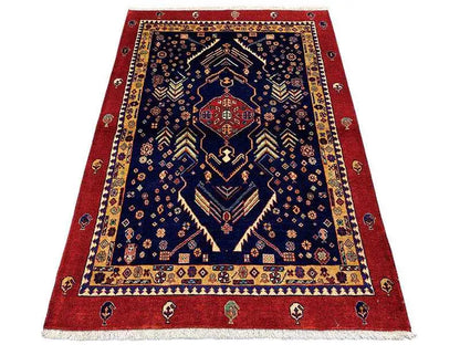 Dark blue rug with a red border and geometric medallion design, short fringes.