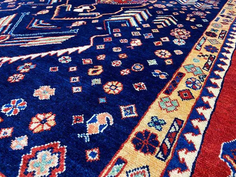 Carpet detail: dark blue pile with colorful geometric motifs and borders.