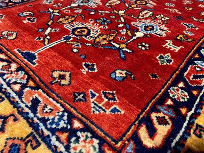 Oriental rug in detail: red background with colorful floral ornaments and a blue border