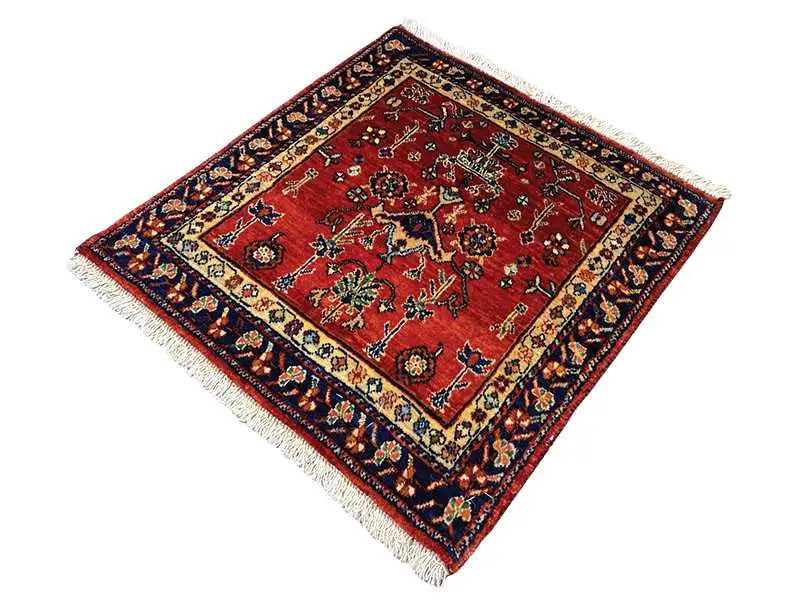 Square rug with a red field, dark blue border, and fringe