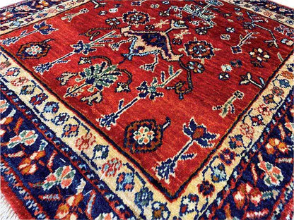Carpet detail with a red background, multicolored floral ornaments, and a blue border