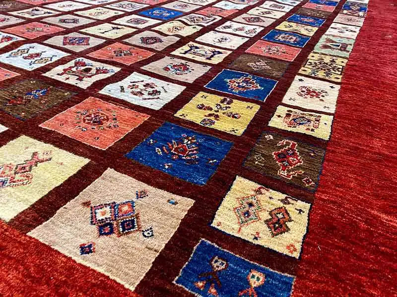 Carpet surface with square patchwork in shades of red, blue, and beige