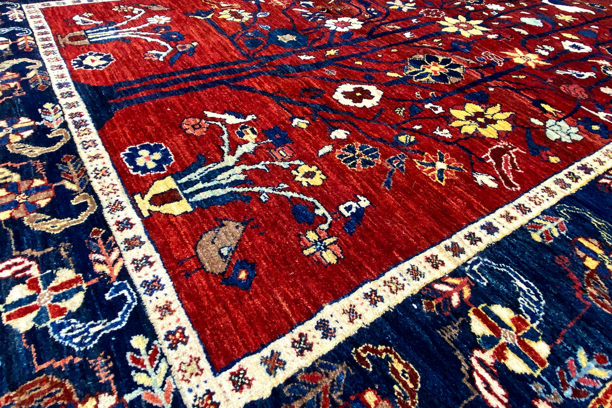Close-up of a rug: red field with small animal motifs and a blue border