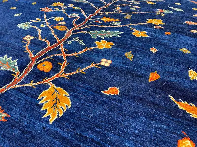 Carpet detail: dark blue pile with delicate tree branches and colorful leaves