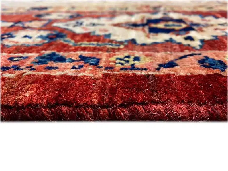 Oriental rug detail: dense pile with a red background and blue-red ornaments