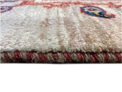 Close-up of the carpet edge: beige pile, red patterned border, and fringe
