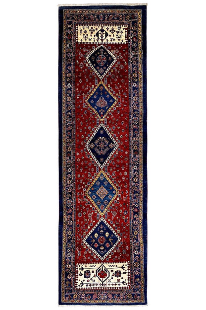 Narrow Oriental runner rug with a red field, dark blue border, and diamond motifs