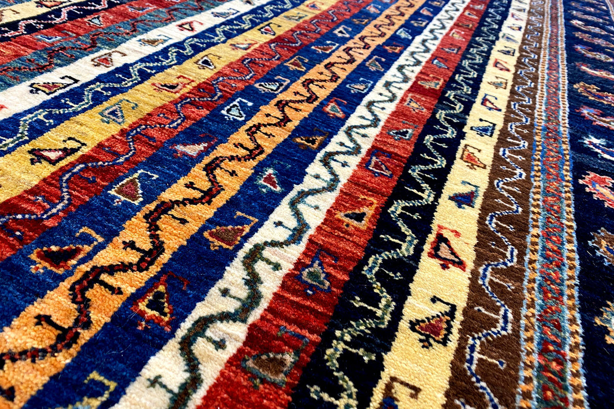Oriental rug detail with blue and yellow stripes and multicolored ornaments in the pile