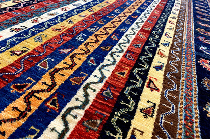 Oriental rug detail with blue and yellow stripes and multicolored ornaments in the pile