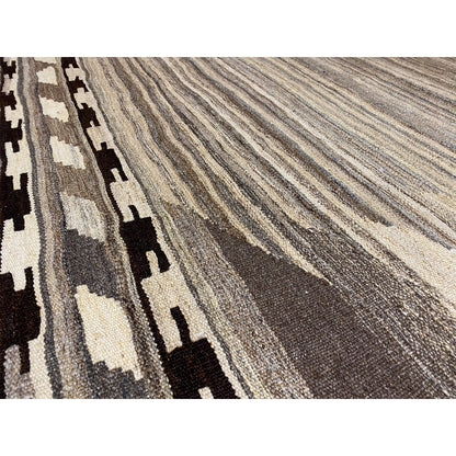 Close-up of a kilim rug: striped texture in gray, beige, and black with a border