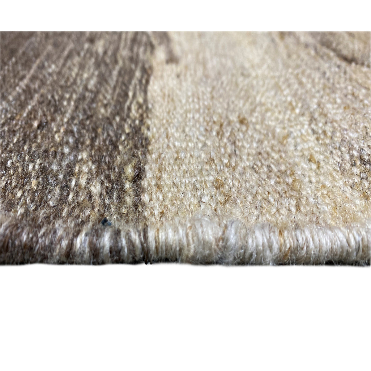 Close-up of a carpet edge with pile texture, gray and beige fibers, short fringes