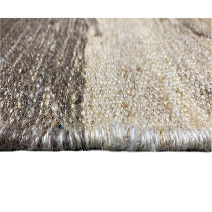 Close-up of a carpet edge with pile texture, gray and beige fibers, short fringes