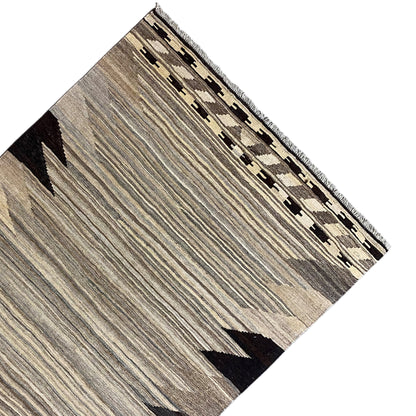 Kilim rug corner with a border of squares, gray stripes, and black triangles