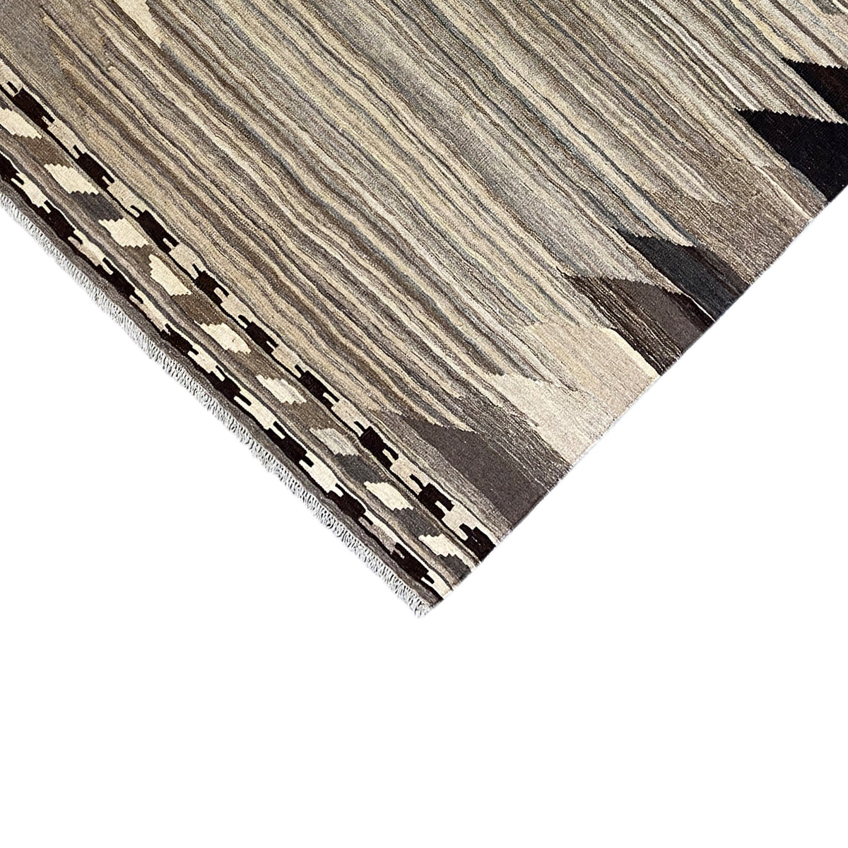 Detailed view of edge with fringe and geometric border, greige pattern, black