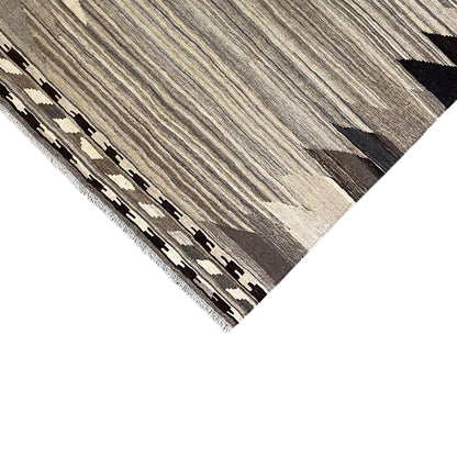 Detailed view of edge with fringe and geometric border, greige pattern, black
