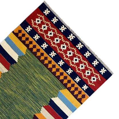 Kilim rug corner with fringe and patterned stripes in green, red, and blue