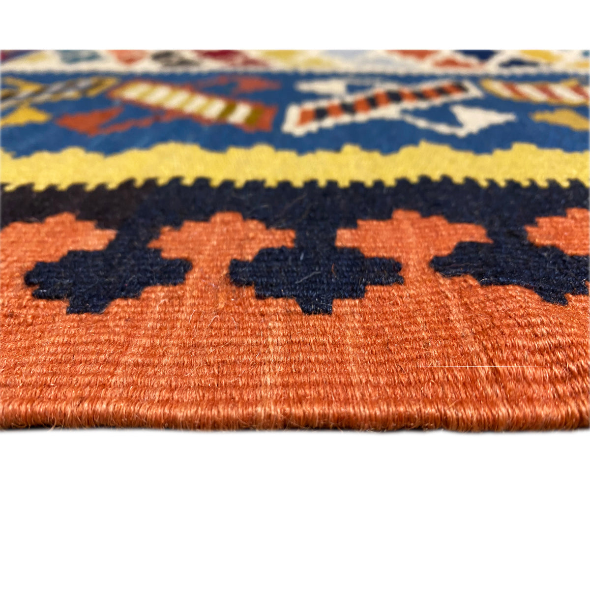 Kilim rug detail: orange background with dark and yellow leaf shapes and dot pattern