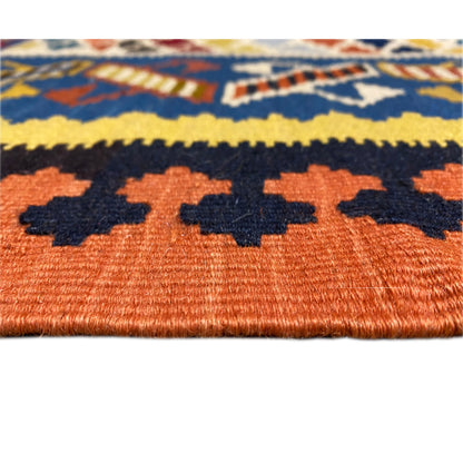 Kilim rug detail: orange background with dark and yellow leaf shapes and dot pattern