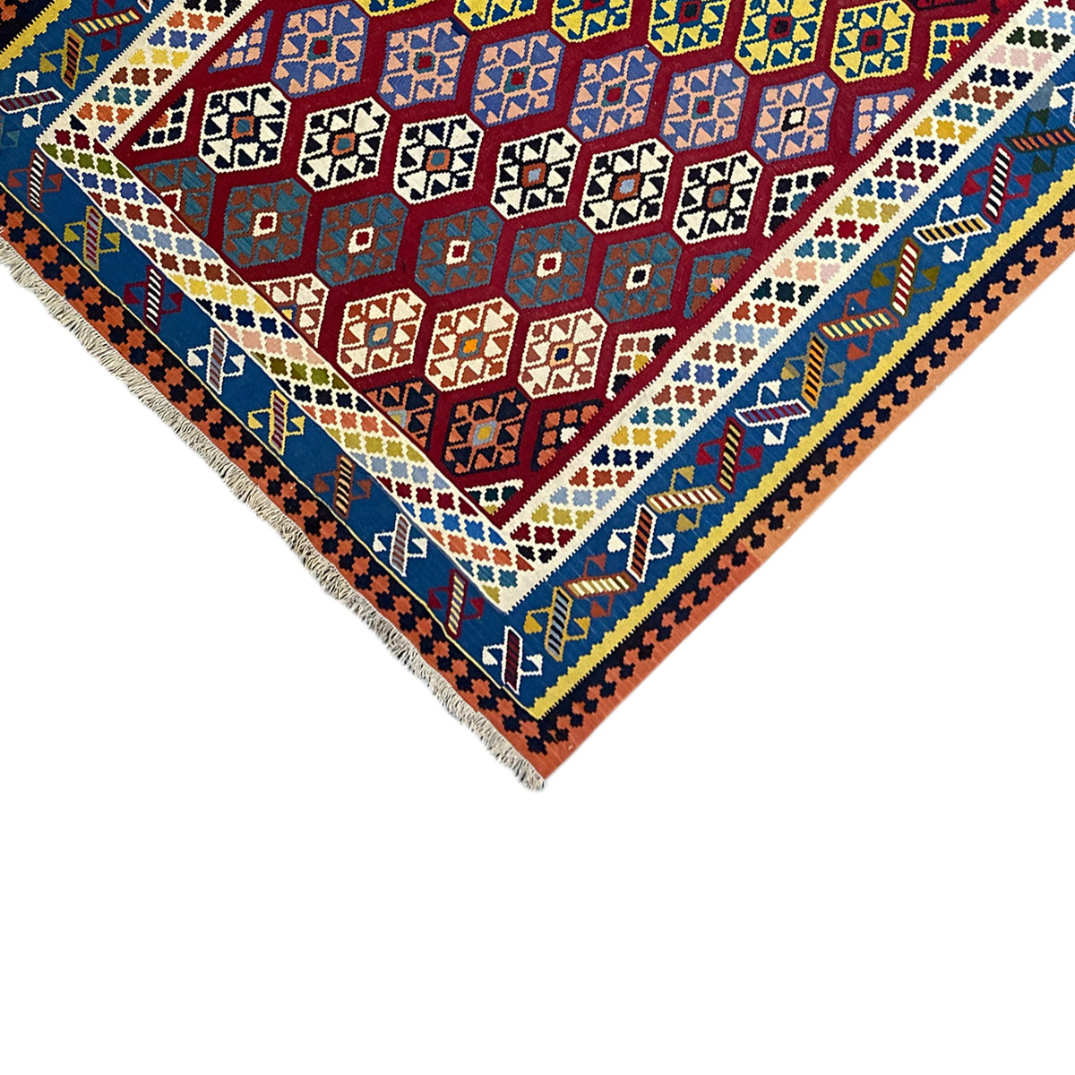 Kilim rug corner with fringes: blue border field, red central pattern, and multicolored diamonds