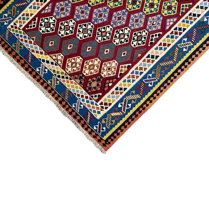 Kilim rug corner with fringes: blue border field, red central pattern, and multicolored diamonds