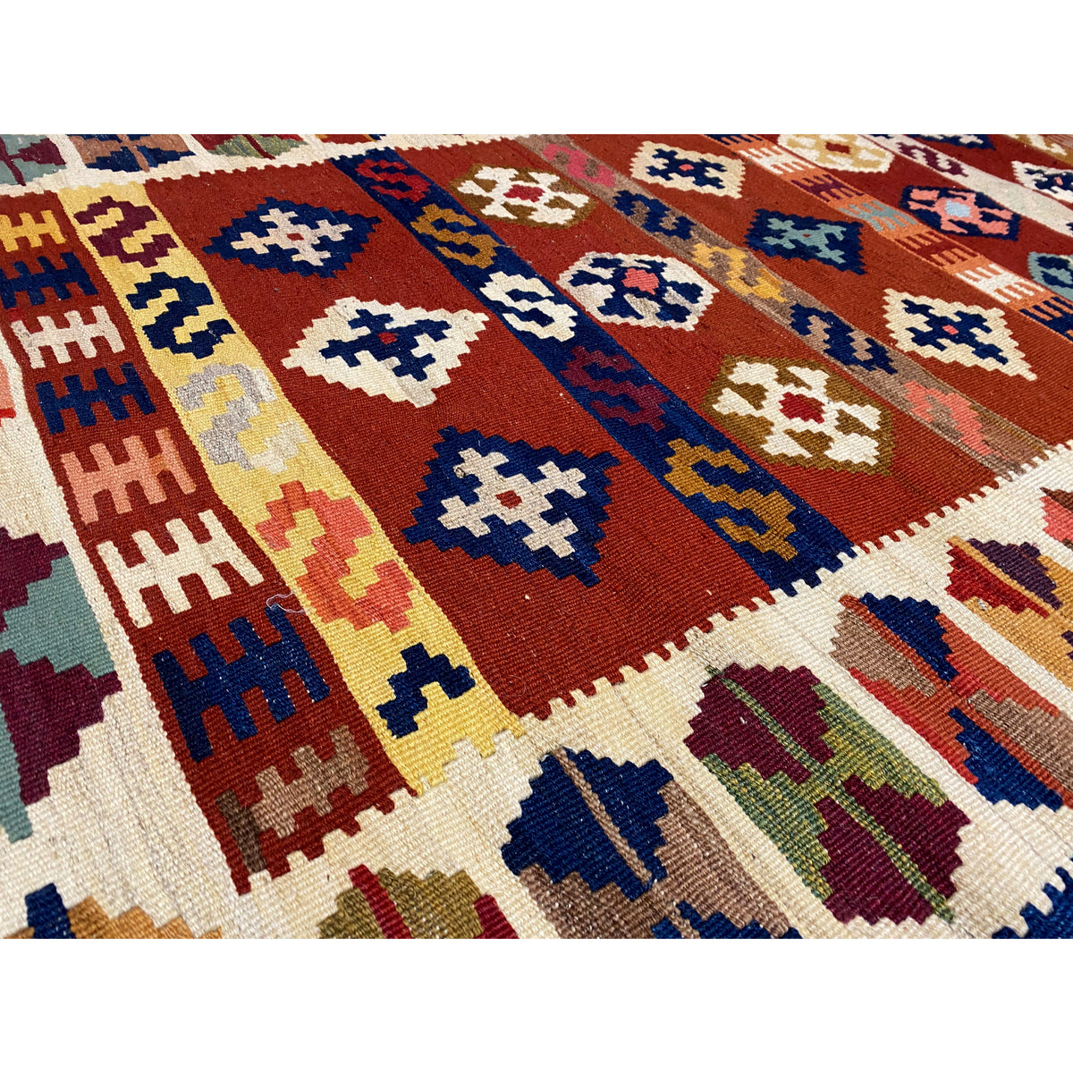 Close-up of the kilim pattern: cross and diamond shapes in shades of red, blue, and cream.