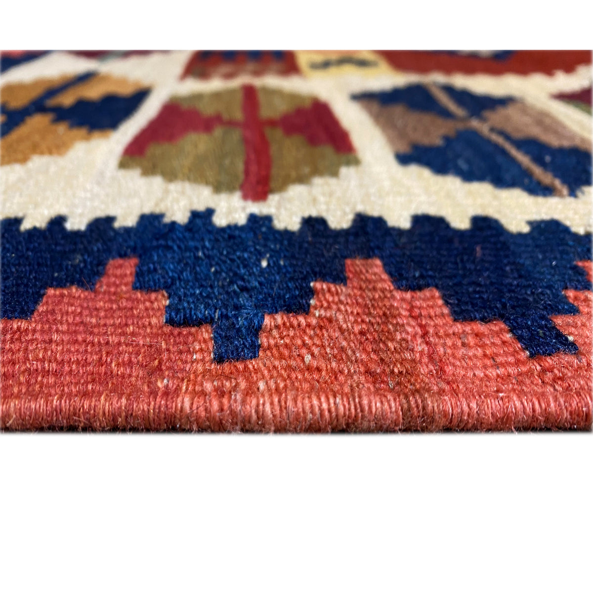 Detail of the fringe edge and weave structure: color blocks in blue, red, and cream.