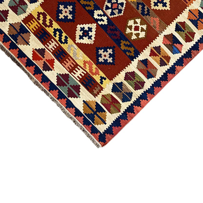 Corner detail of the kilim rug with a border, colorful motifs, and short fringes.
