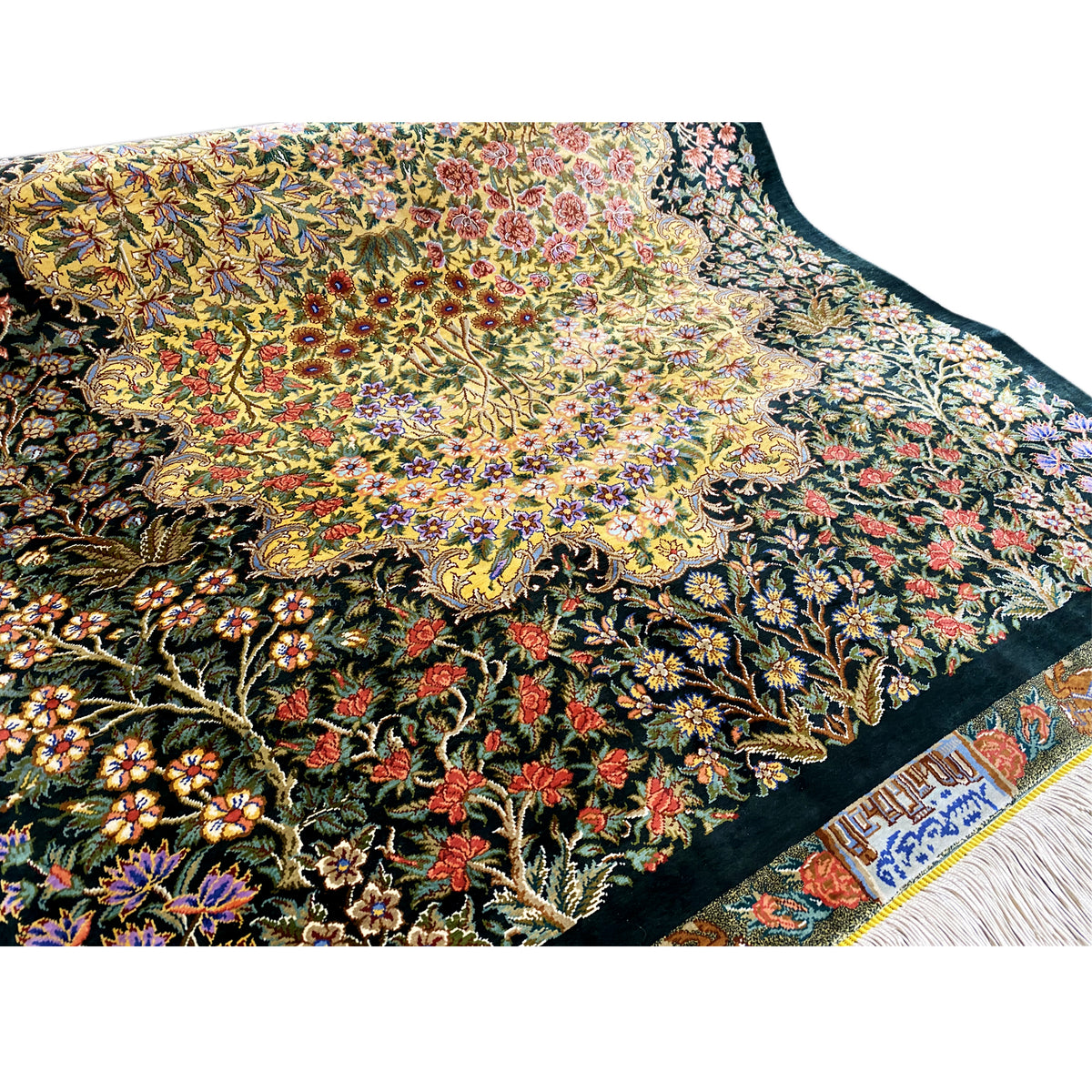 Silk rug with a dense floral pattern and border, dark background, fringes along the edge