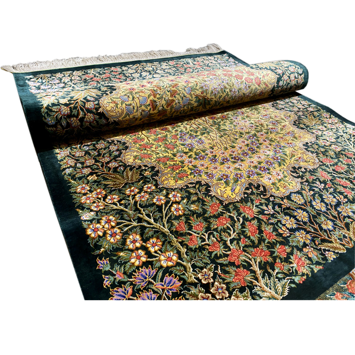 Silk rug with a dark background and lush floral pattern, rolled with fringes