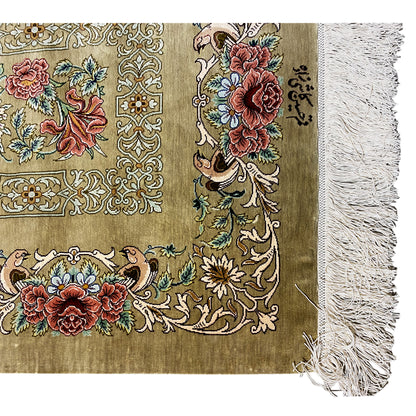 Close-up of a silk rug at the edge: large flowers in the pattern, olive-brown background, fringes