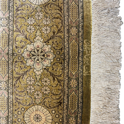 Carpet detail with a golden-brown pattern, floral ornaments, border stripes, and white fringes