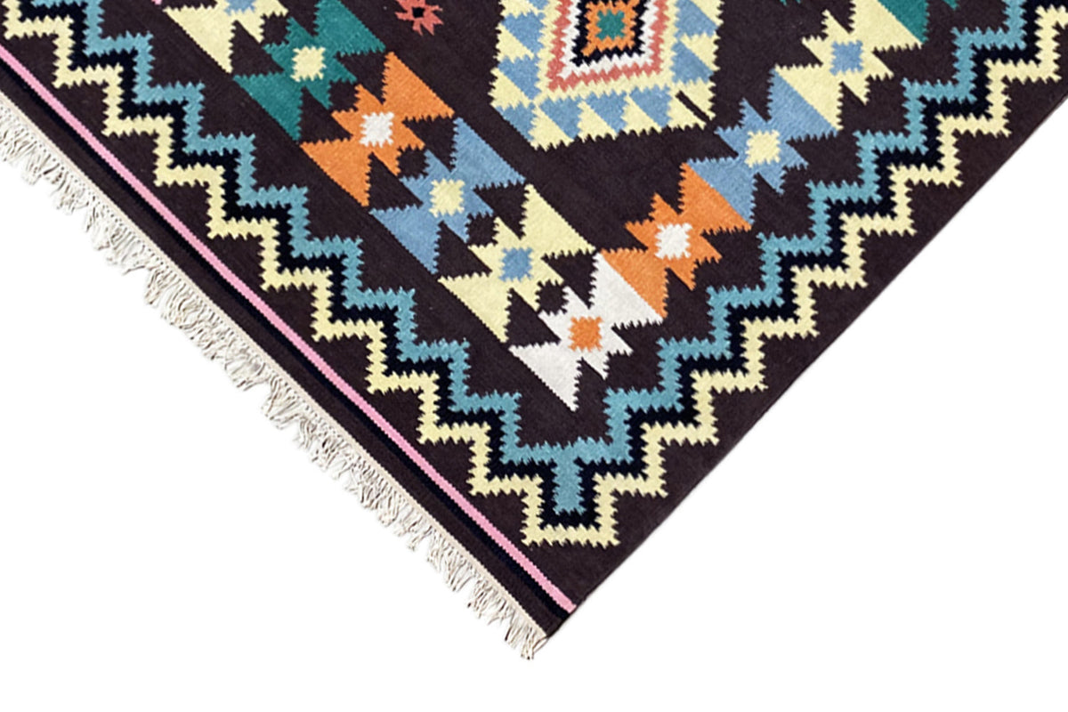 Rug corner with zigzag and triangular patterns, colorful accents, and fringes