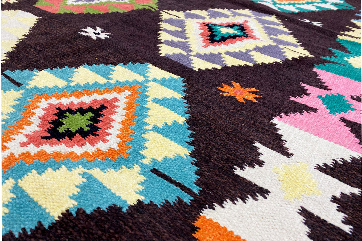 Rug pile with colorful diamonds, stars, and striped patterns on a dark background