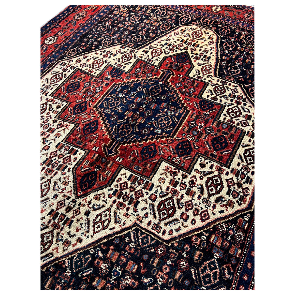 Rug with a central medallion and bold pattern in dark blue, red, and beige.